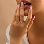 Close-up of a hand with a 14k gold filled opal stone ring on a beige background